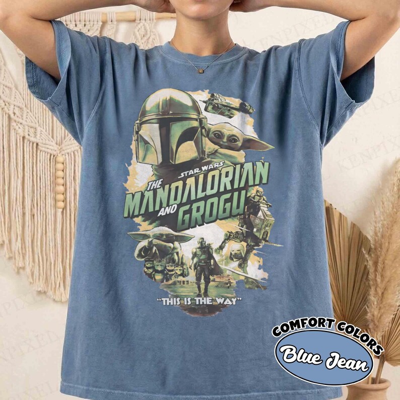 Pu&ograve; includere: T-shirt blu jeans con grafica di Star Wars con "The Mandalorian and Grogu". Il design include personaggi e la frase "THIS IS THE WAY". La maglietta &egrave; etichettata "COMFORT COLORS".