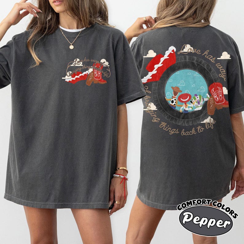 May include: A charcoal gray short-sleeve t-shirt featuring a small graphic on the front left chest and a large graphic on the back. Both graphics depict a red cowboy boot and the text Love has a way of bringing things back to life.