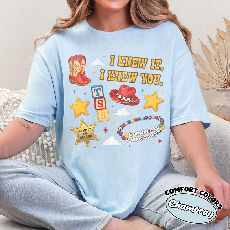 Peut inclure: Un t-shirt bleu clair avec une impression graphique comprenant le texte I KNEW IT, I KNEW YOU, une botte de cowboy rouge, un chapeau de cowboy rouge, trois blocs alphab&eacute;tiques, deux &eacute;toiles jaunes, un badge de sh&eacute;rif dor&eacute; et un bracelet de perles.