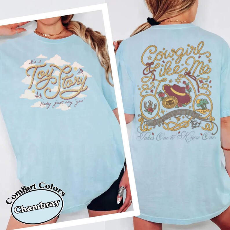 May include: A light blue t-shirt featuring a front graphic with the text "It's a Toy Story, baby, just say yes" in rope-style lettering over clouds. The back graphic displays "Cowgirl like me" and "Takes one to know one" with rope borders, a hat, and icons.