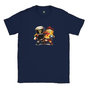 Puede incluir: Camiseta azul marino con una ilustración de dibujos animados de dos personajes de cerveza en poses de boxeo. Uno es una pinta de Guinness con una bandera irlandesa, el otro una lata de Tennent's con un kilt escocés.
