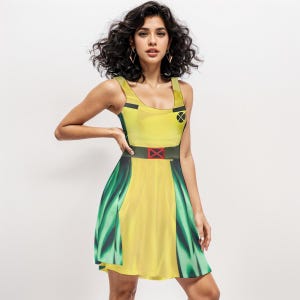 Puede incluir: Un vestido amarillo sin mangas con cinturón negro y rojo y detalles verdes. El vestido presenta un símbolo X negro en el pecho y una X roja en el cinturón. El vestido es un diseño inspirado en disfraces.