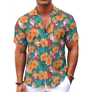 Puede incluir: Camisa de manga corta con botones y un estampado tropical vibrante. El fondo turquesa está cubierto de flores de hibisco naranja, hojas verdes e imágenes de dibujos animados de los siete enanitos. La camisa tiene un cuello clásico y se lleva abierta.