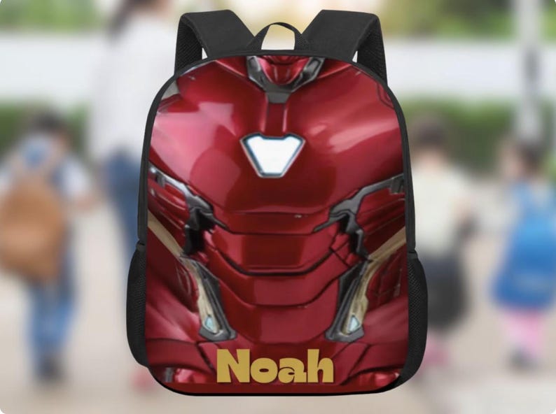 Puede incluir: Una mochila roja y dorada con un dise&ntilde;o inspirado en la armadura de Iron Man. La mochila tiene correas negras y el nombre "Noah" en letras doradas en la parte inferior. El dise&ntilde;o incluye una pieza pectoral blanca brillante.