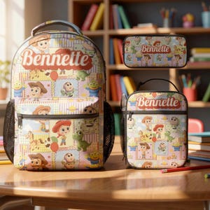 Op de afbeelding: Een set bestaande uit een rugzak, lunchtas en etui met een herhalend patroon van stripfiguren en de naam "Bennette" in rood schrift. De items hebben een lichtblauwe, roze en gele rasterachtergrond met diverse illustraties.