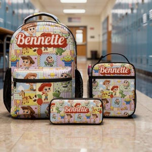 Op de afbeelding: Een set bestaande uit een rugzak, lunchtas en etui met een herhalend patroon van Toy Story-stripfiguren. Elk item toont de naam Bennette in een rood scriptlettertype op een lichtblauwe, gele en paarse achtergrond met een ruitjespatroon.