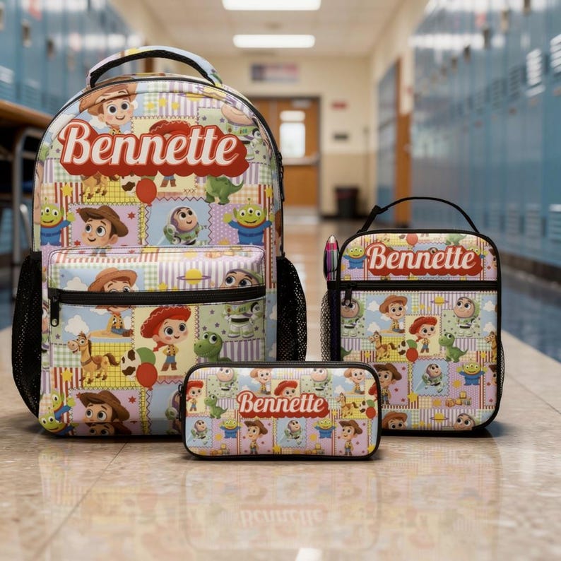Op de afbeelding: Een set bestaande uit een rugzak, lunchtas en etui met een herhalend patroon van Toy Story-stripfiguren. Elk item toont de naam Bennette in een rood scriptlettertype op een lichtblauwe, gele en paarse achtergrond met een ruitjespatroon.