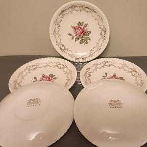Peut inclure: Ensemble d'assiettes anciennes en porcelaine blanche avec une rose rose et une bordure dorée. Les assiettes ont un bord festonné et sont marquées "22K Gold".