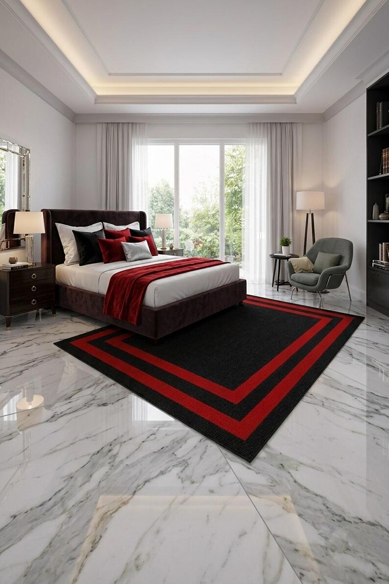 May include: A rectangular area rug featuring a solid black center bordered by two distinct red stripes. The rug is positioned on a white marble floor with grey veining, situated in a bedroom with a dark brown bed frame and red bedding accents.
