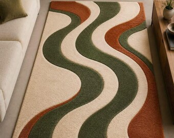 May include: A rectangular area rug featuring a repeating wavy pattern of thick, textured bands in cream, forest green, and burnt orange. The rug has a high-pile, tufted surface that creates a distinct visual depth between the contrasting colour waves.