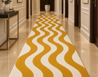 May include: A long runner rug featuring a repeating wavy pattern in mustard yellow and cream white. The rug has a rounded end and is positioned centrally along a hallway floor, extending from the foreground towards the back of the corridor.
