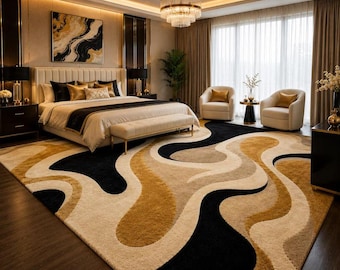 May include: A large area rug featuring a flowing, abstract wave pattern in shades of black, gold, and cream. The rug has a thick, textured pile and covers the floor of a bedroom, extending from the foot of the bed towards the foreground.