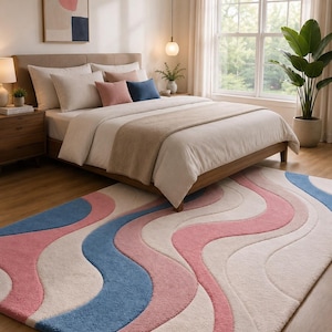 May include: A bedroom scene featuring a large bed with neutral-toned bedding and decorative pillows. A colorful rug with wavy patterns in pink, blue, and cream tones is on the floor. A framed abstract art piece hangs on the wall.