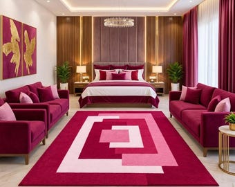 May include: A large rectangular area rug featuring a geometric pattern of nested rectangles in shades of deep magenta, bright pink, and soft white. The rug is centred in a room with magenta sofas, a bed with matching bedding, and gold accents.