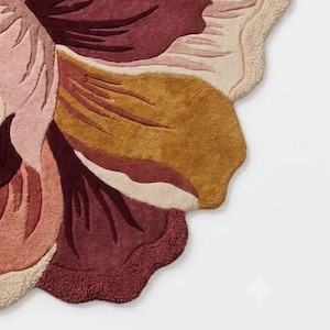 May include: A tufted rug featuring a large, stylized floral design with organic, scalloped edges. The color palette consists of deep burgundy, warm mustard yellow, soft blush pink, and cream tones, creating a layered, textured petal effect.
