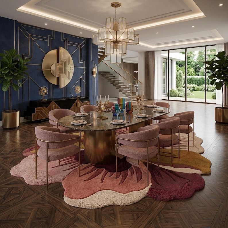 May include: A dining room featuring an oval marble table with a gold base, surrounded by eight pink upholstered chairs with gold frames. A large, multi-colored floral-shaped area rug sits on a dark wood floor beneath the table and chairs.