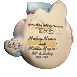 May include: A ceramic figurine of Mickey Mouse and Minnie Mouse, commemorating their 60th birthday. The figurine is white with blue and pink accents. The text "Mickey Mouse and Minnie Mouse 60th Birthday 1928-1988" is visible.