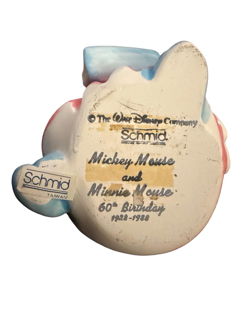 May include: A ceramic figurine of Mickey Mouse and Minnie Mouse, commemorating their 60th birthday. The figurine is white with blue and pink accents. The text "Mickey Mouse and Minnie Mouse 60th Birthday 1928-1988" is visible.
