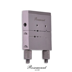 Könnte beinhalten: Eine rechteckige, metallisch graue Industriekomponente mit der eingravierten Aufschrift Rosemount. Das Gerät hat ein geteiltes Gehäusedesign mit zwei runden, gerändelten Einstellknöpfen an der Basis und mehreren kleinen, präzisionsgebohrten Löchern.