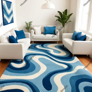May include: A large, blue and white patterned rug dominates a living room scene. The rug's design features flowing, wavy lines in shades of blue and white. White sofas with blue cushions and a matching artwork complete the room's decor.