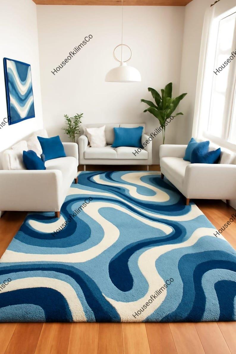 May include: A large, blue and white patterned rug dominates a living room scene. The rug's design features flowing, wavy lines in shades of blue and white. White sofas with blue cushions and a matching artwork complete the room's decor.