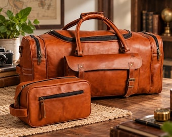 May include: A tan leather holdall with black zips and a matching smaller rectangular wash bag. The holdall features a front flap pocket with two buckle straps and a top handle. Both bags have a smooth finish and brass-toned metal hardware.