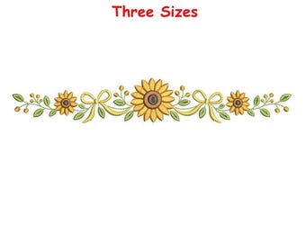 Può includere: Un disegno per ricamo con un girasole centrale affiancato da due girasoli più piccoli, nastri gialli, foglie verdi e piccole bacche disposte in linea orizzontale. Il testo "Three Sizes" è stampato in rosso sopra il motivo floreale.