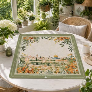 May include: A rectangular game mat featuring a watercolor illustration of a cityscape with a golden dome and surrounding buildings. The mat has a green border with text and floral accents. The mat is on a white table.