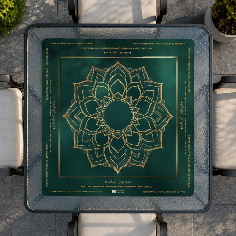 May include: A square glass-topped table with a green and gold game board. The board features a gold floral design in the center and text around the edges. The table is surrounded by four chairs.
