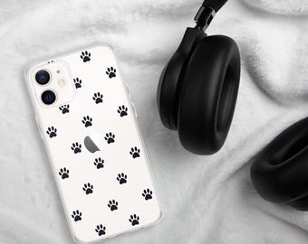 May include: A clear phone case with a pattern of black paw prints. The phone case is next to a pair of black over-ear headphones.