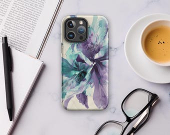 Puede incluir: Funda de teléfono con un diseño floral en tonos turquesa y morado. La funda está sobre una superficie de mármol, junto con una taza de café, gafas y un cuaderno.