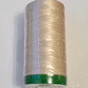 May include: A spool of beige thread wrapped in clear plastic with a green top and bottom.