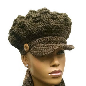 May include: A brown crocheted newsboy cap with a button detail and a matching brown crocheted infinity scarf.
