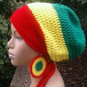 May include: A red, yellow and green crocheted beanie with a long red crocheted tie. The beanie has a rounded shape and is made with a thick yarn. The tie is long enough to be worn as a scarf.