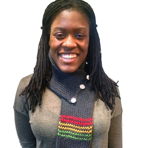 Puede incluir: Una mujer con una camisa gris de manga larga y una bufanda de punto gris y multicolor. La bufanda tiene un patrón de rayas rojas, amarillas y verdes.