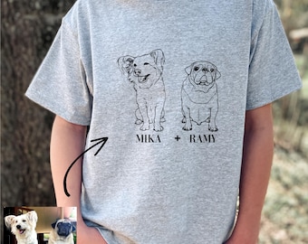 Peut inclure: T-shirt gris clair avec des illustrations au trait de deux chiens, avec les noms "MIKA" et "RAMY" imprimés en dessous. Le coin supérieur gauche de l'image indique "35 couleurs disponibles".