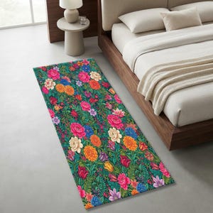 May include: A rectangular area rug featuring a dense, vibrant botanical pattern on a dark green background. The design includes various flowers in shades of pink, orange, yellow, blue, and cream, interspersed with green foliage and fern-like leaves.