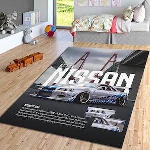May include: A rectangular black rug featuring a silver Nissan Skyline GT-R sports car with blue detailing. The rug has the word "NISSAN" in large white letters and the text "GT R34".