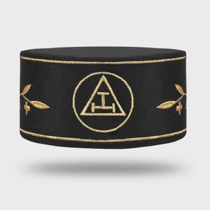 Könnte beinhalten: Schwarzer zylindrischer Hut mit goldgestickten Verzierungen und Akzenten. Der Hut hat ein goldenes Emblem in einem Kreis und goldene Blattmotive. Der Hut ist wahrscheinlich für zeremonielle oder formelle Anlässe gedacht.
