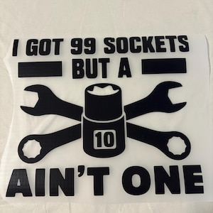 Könnte beinhalten: Schwarze Grafik mit dem Text "I GOT 99 SOCKETS BUT A AIN'T ONE". Das Design umfasst einen Steckschlüssel, zwei gekreuzte Schraubenschlüssel und die Zahl 10.
