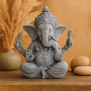 Peut inclure: Une statue en pierre grise de Ganesha, la divinité hindoue, assise en méditation. La figure à tête d'éléphant est ornée d'une couronne et de bijoux, tenant une fleur de lotus. La statue est posée sur une surface en bois.