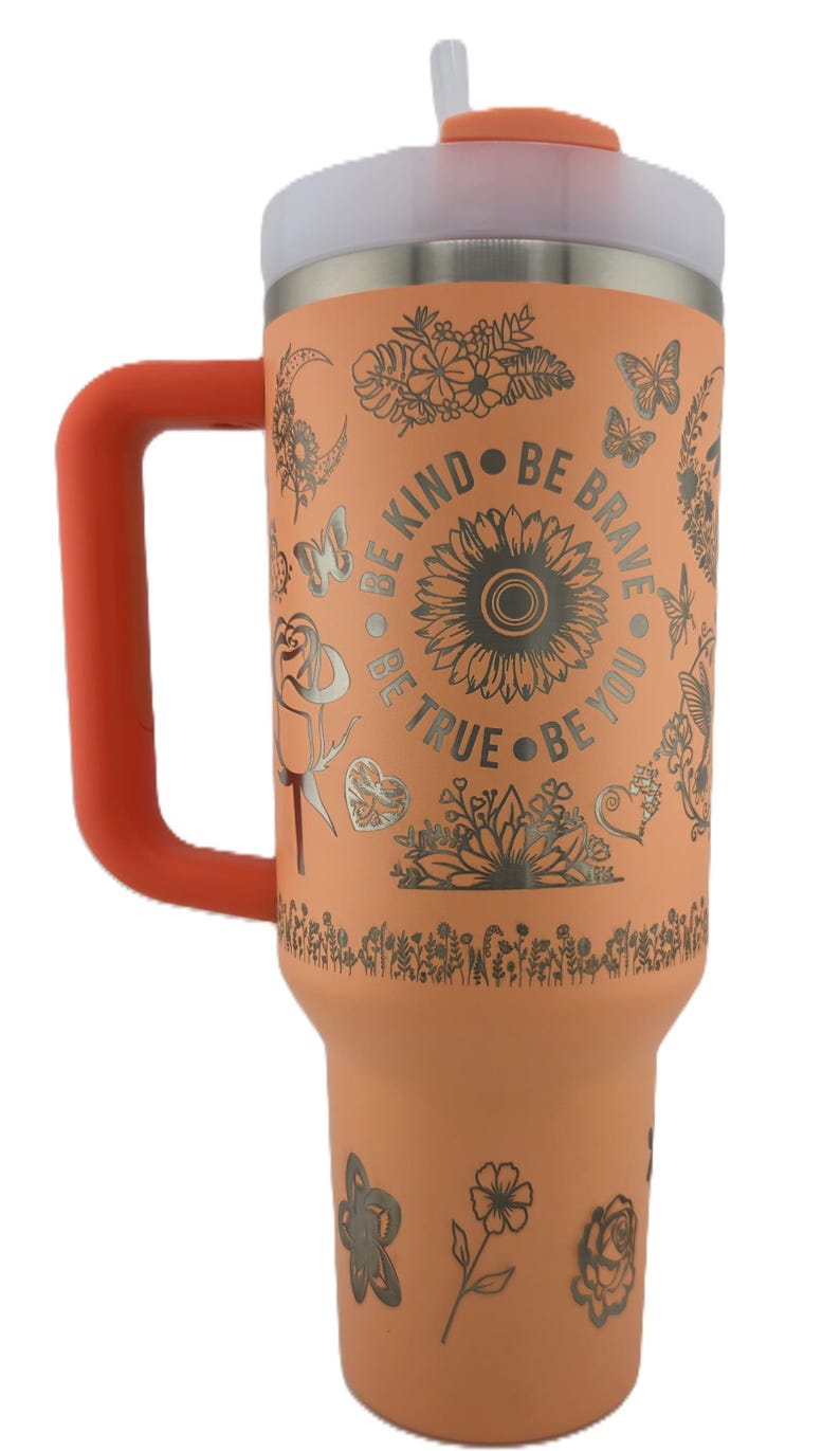 May include: Peach-colored insulated tumbler with a handle, lid, and straw. The tumbler is decorated with floral and butterfly designs, and the words "Be Kind, Be Brave, Be True, Be You".