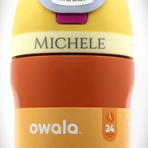 Pu&ograve; includere: Una borraccia Owala dai colori vivaci, arancione, giallo e viola. Il tappo riporta la scritta "Lift to Unlock". La borraccia, con il marchio "MICHELE", &egrave; a prova di perdite e isolata. Progettata per mantenere i liquidi freddi per 24 ore.