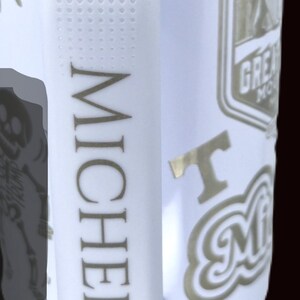 May include: White travel mug with a gold rim and handle. The mug features the name "MICHELE" in gold lettering, along with various gold-colored graphics and text, including "Great Smoky Mountains" and "I Love Michele".