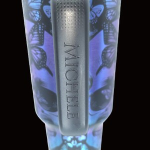 May include: A white ceramic mug with a black handle and the text "But First, Coffee" in a black, bold font. The mug is on a white surface.