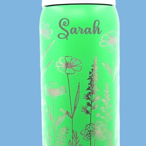 Pu&ograve; includere: Borraccia verde con un design floreale e il nome "Sarah" in corsivo. La bottiglia ha una parte superiore bianca e un manico viola. Il marchio "owala" &egrave; stampato sulla bottiglia.