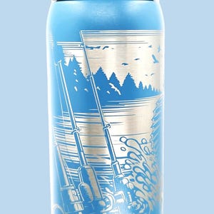 May include: Blue insulated water bottle with a fishing-themed design. The bottle features a detailed illustration of fishing rods, water, trees, and birds. The bottle has a white lid and the brand name "awala" is visible.