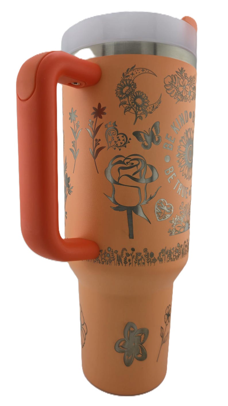 May include: An orange insulated tumbler with a white lid and orange handle. The tumbler is decorated with floral and butterfly designs, along with the words "Be Kind, Be True".