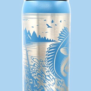 May include: Blue water bottle with a silver fishing scene design. The illustration features a fish jumping out of the water, a fishing rod, and a lake with trees and birds. The lid is gray and white.