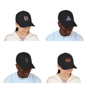 Op de afbeelding: Een collectie van vier zwarte baseballpetten, elk voorzien van een uniek geborduurd embleem op de voorzijde. De ontwerpen bestaan uit een roze cirkel met een streep, een blauwe geometrische driehoek, een paars harp-symbool en een rood met gouden embleem.